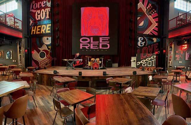 view from dining area of wood tables chairs and stage at blake sheltons ole red orlando icon park