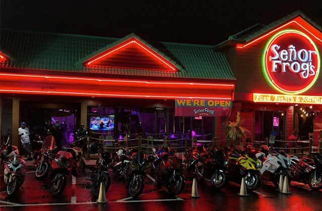 front exterior of restaurant at night with red neon lighting and row of motorcycles at senor frogs orlando
