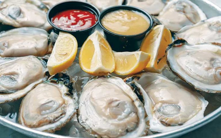 plate of open oysters on ice with lemon wedges and red and yellow sauces at the juicy crab international drive orlando