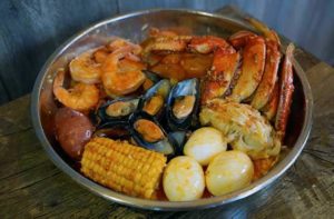 seafood boil bowl with crab legs shrimp mussels lobster tail eggs cob corn and potatoes at the juicy crab orlando