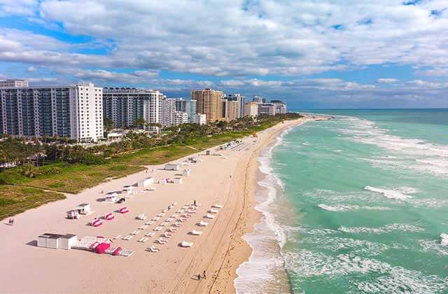 aerial view of miami beach with green water surf high rise condos and hotels for relax on a beach page