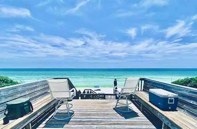 boardwalk over dunes with benches coolers patio chairs and pristine beach with blue gradient water and clear sky for relax on a beach page