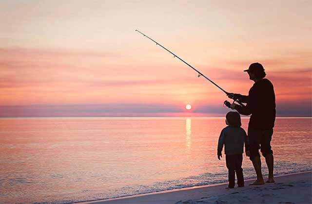 father and son fishing on beach with sun setting for florida sports page