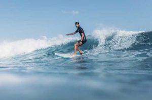 man in wet suit surfing a wave at jacksonville for relax on a beach page