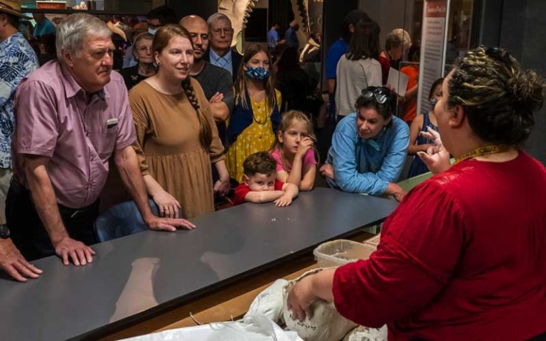 family crowd looks on as guide explains archaeology of dinosaur bones for science up close fantastic fossils at florida museum gainesville
