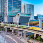 arial view of brightline express train tracks above roads going between skyscrapers in Miami