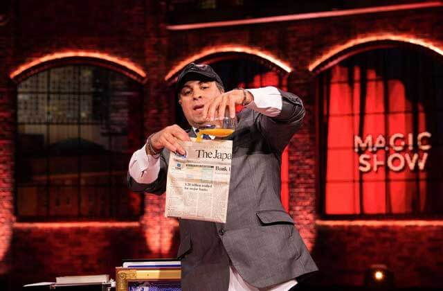 magician on stage pours orange juice into folded newspaper at icons of magic show orlando