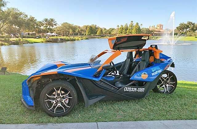 orange and blue gull-wing slingshot parked near lake with fountain at central florida slingshots orlando