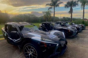 row of polaris slingshot vehicles for rent in parking lot with sunset and palm trees at central florida slingshots orlando