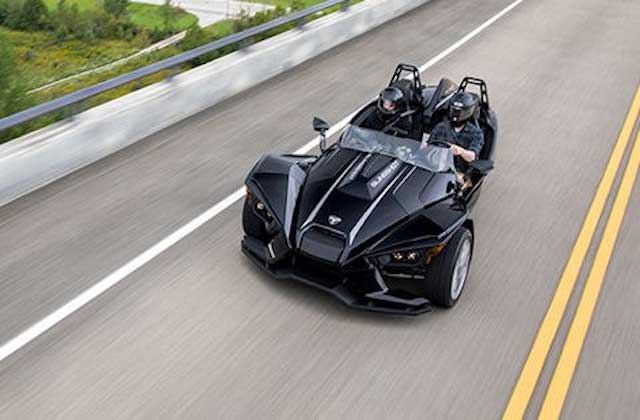slingshot vehicle drives down highway with two helmeted riders at central florida slingshots orlando