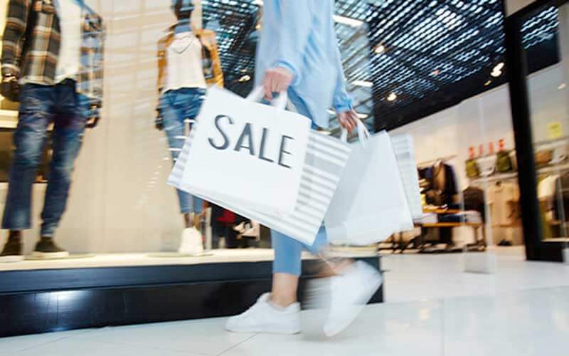 shopper in mall with bags marked sale passing mens clothing store for orlando black friday sales blog