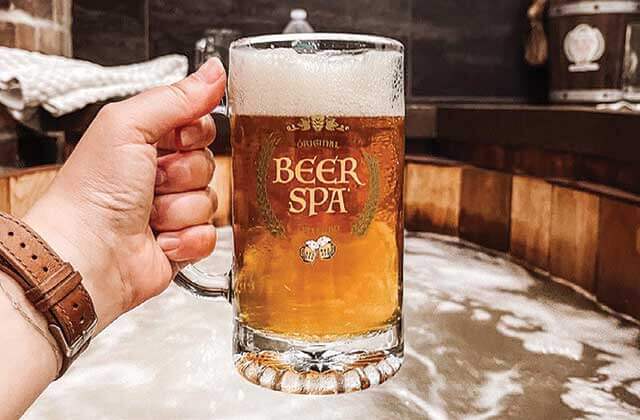 beer spa orlando hand holding stein of beer sitting in beer soak tub