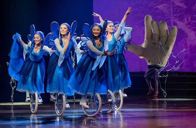 five females wearing blue fairy costumes balance on unicycles at the Cirque Du Soleil Disney Drawn To Life Show at Disney Springs Orlando.