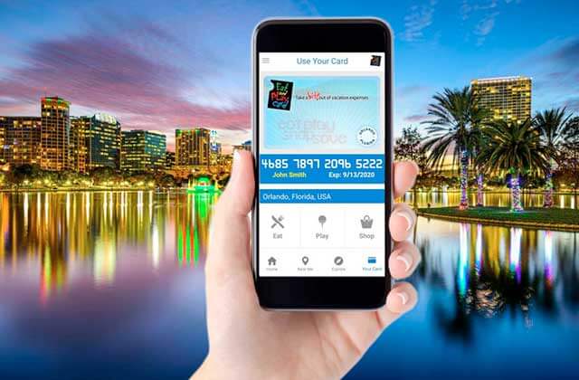 hand holding smartphone with membership card app on screen and downtown orlando at night in background for eat and play orlando discount card