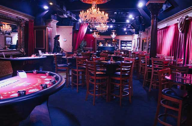 interior view of jewel speakeasy bar and lounge with glass chandeliers casino game tables tall chairs and tables
