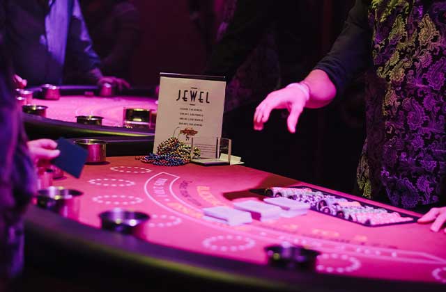 dealers hands at casino game table in a purple lit casino at jewel speakeasy orlando idrive bar