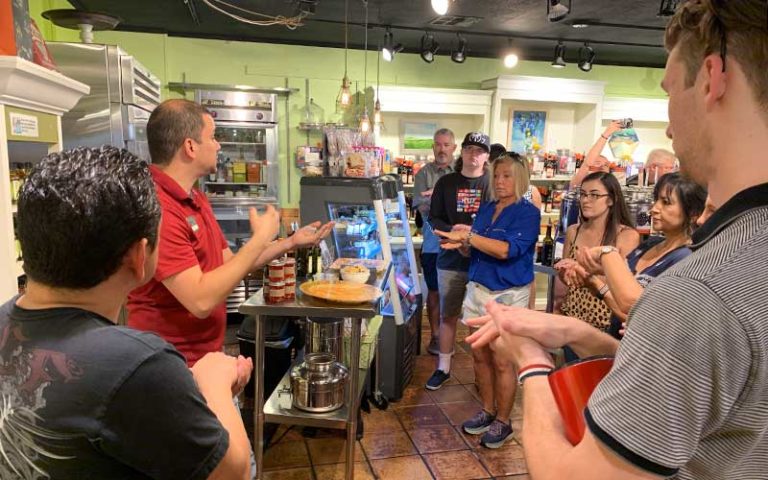 group of adults stand around a commercial kitchen on an original orlando tour leaerning crafts