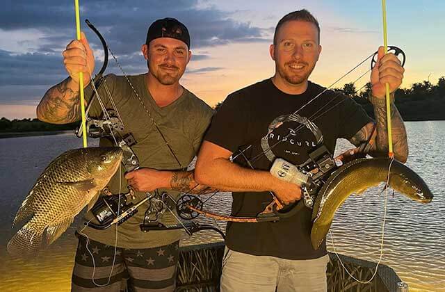 two men holding fish they caught on a boat with sunset in the background for oxranch outfitters orlando kissimmee