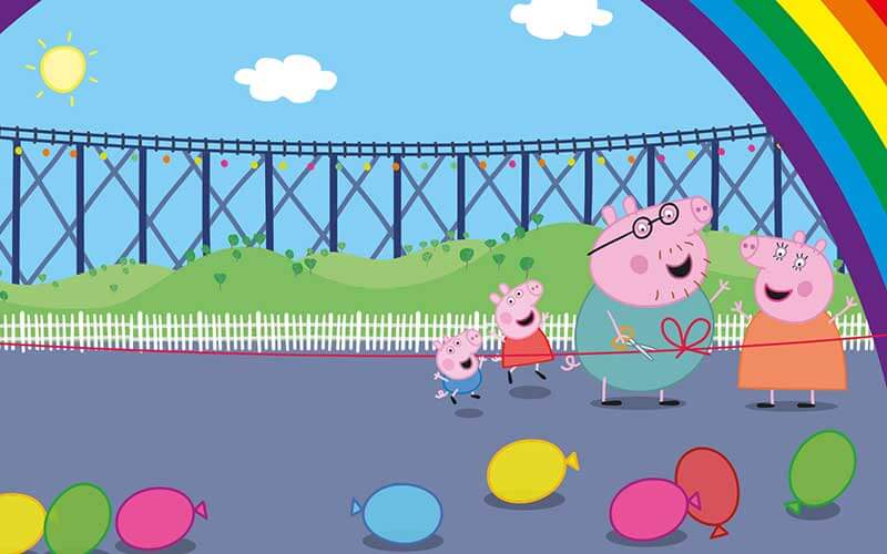 cartoon graphic of peppa pig characters on playground with rainbow and opening ribbon for peppa pig theme park at legoland florida resort
