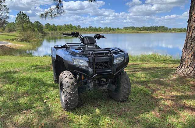 blue atv parked with lake behind and trees at revolution rentals at bone valley atv park