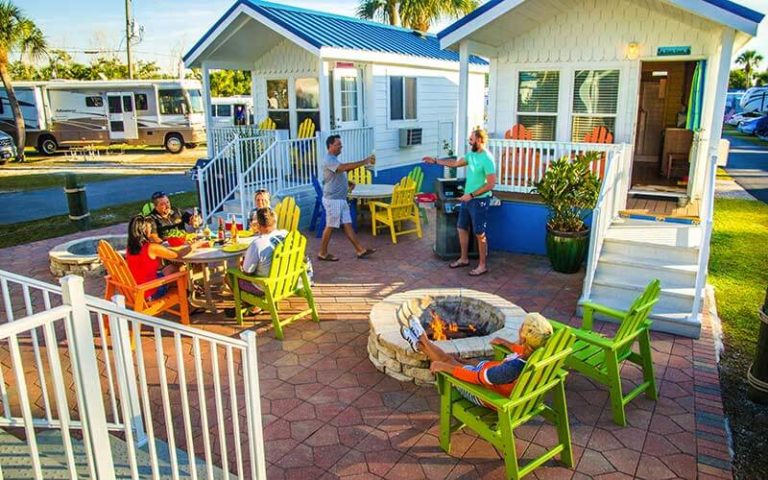 cabins in rv park with shared patio with families talking and eating at naples marco island koa holiday