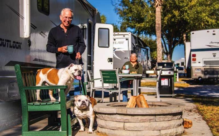 couple with bulldogs standing near fire pit and rvs at orlando southwest koa holiday