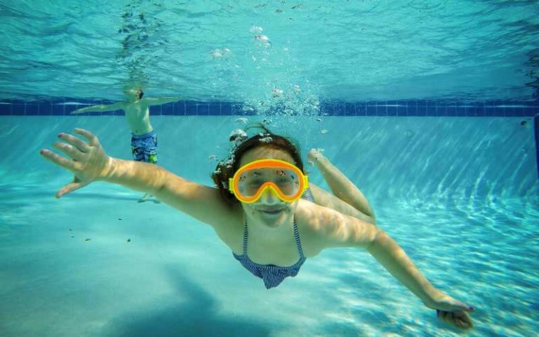 girl with snorkel mask swimming underwater in pool at orlando southwest koa holiday