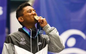 male athlete in a branded jacket kissing a gold medal at the special olympics in oregon