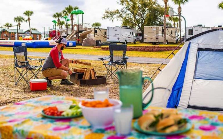 man adding firewood to fire with tent and playground at orlando southwest koa holiday