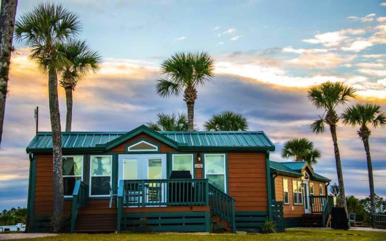 wood cabins with green roofs and palm trees at orlando southwest koa holiday