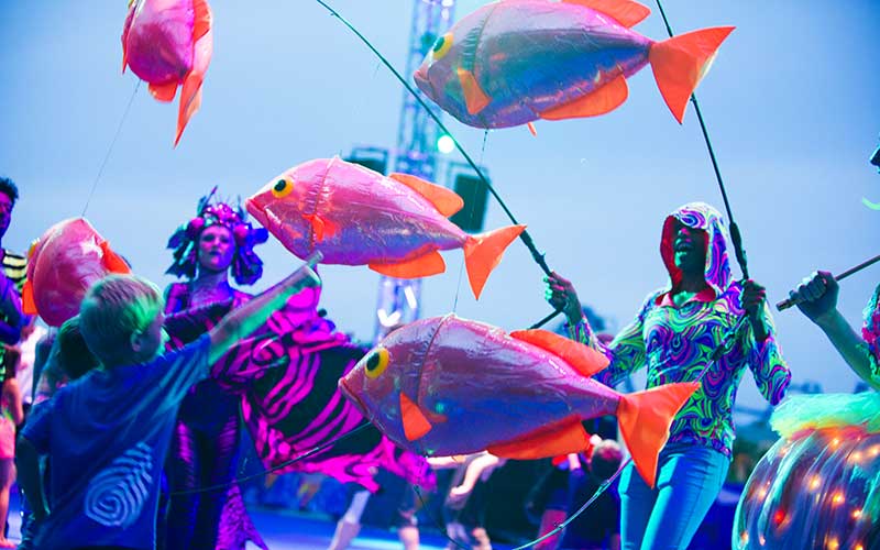 boy points at parade performer with puppet fish neon blacklight effects for electric ocean at seaworld orlando