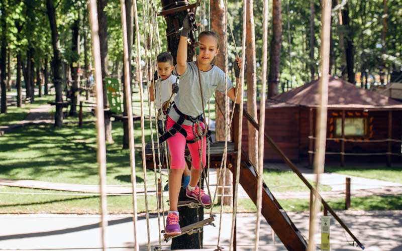 girl and boy climbers on zip line rope course at campground for unplugging on your florida vacation enjoy florida blog