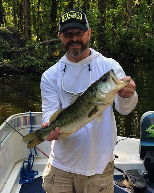 smiling man holding large mouth bass for monster bass fishing charters