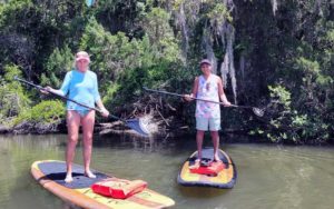 couple standing on paddleboards with cypress trees at three brothers boards