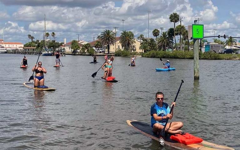 large group tour of paddleboarders on inlet with houses and docks at three brothers boards