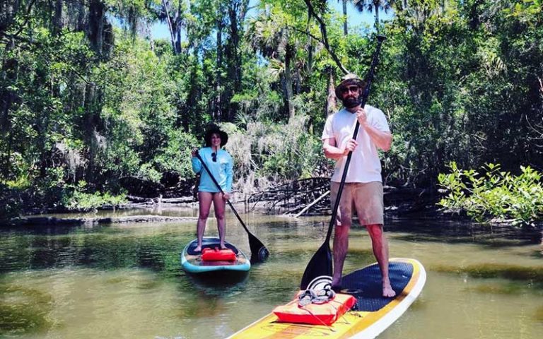 man and woman on stand up boards in swamp at three brothers boards