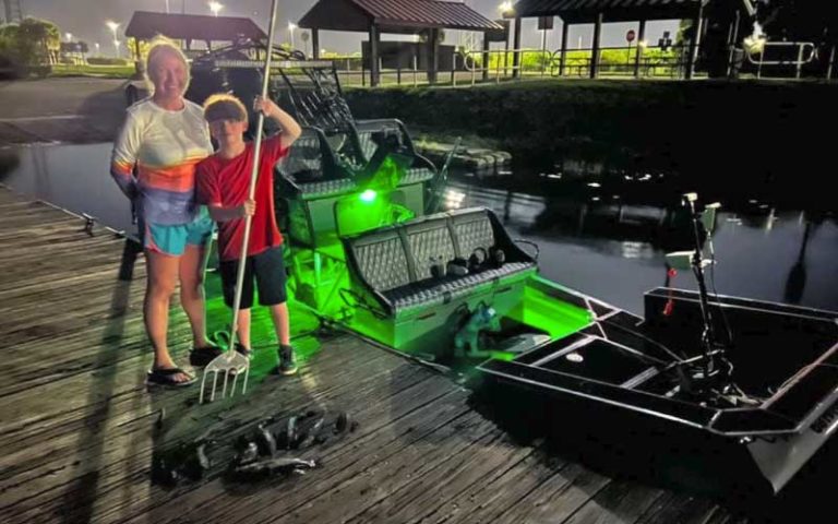 woman and boy with fish on dock at night near fanboat at florida adventure outfitters miami