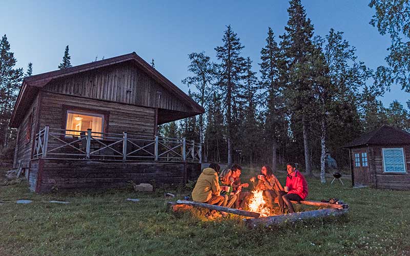 group of friends at a campfire talking with cabin and trees for enjoy florida blog