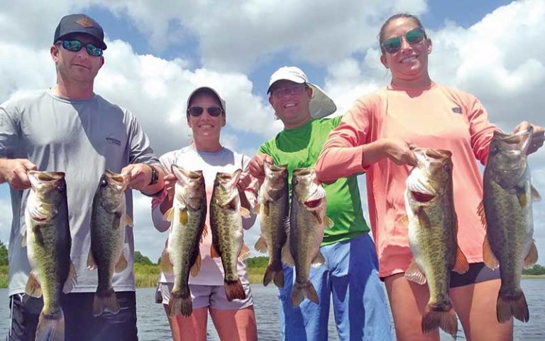 family of four on boat holding two big bass each at david paycheck fishing