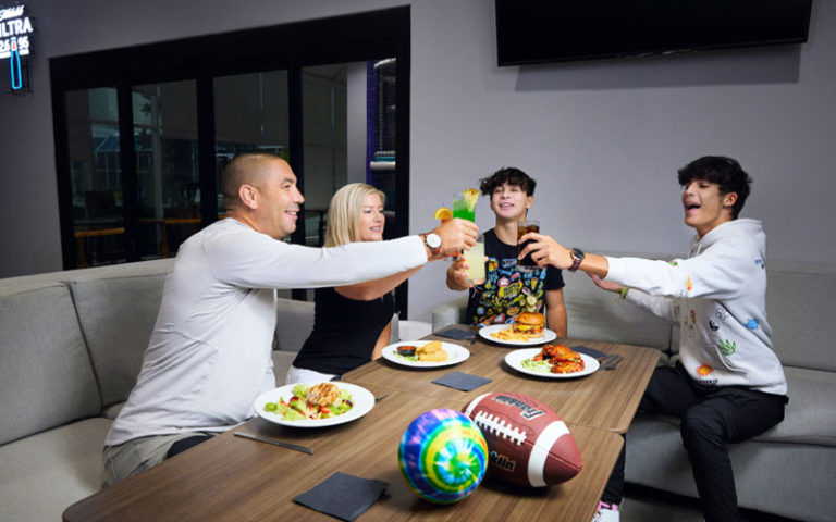 family toasting drinks over table of food at topgolf swing suites