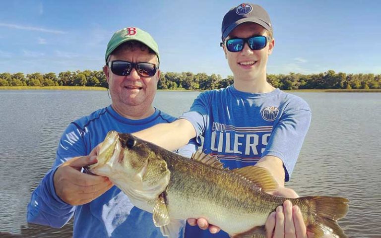father and son holding up large mouth bass at david paycheck fishing