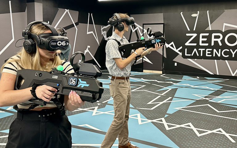 girl and boy wearing vr tech with guns playing combat game with zero latency sign at max action arena icon park