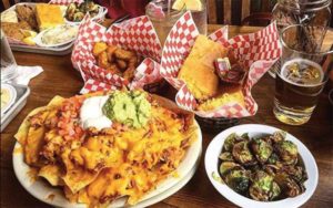 table top spread with several dishes barbecue and sides loaded nachos cornbread beer at brother jimmys icon park orlando