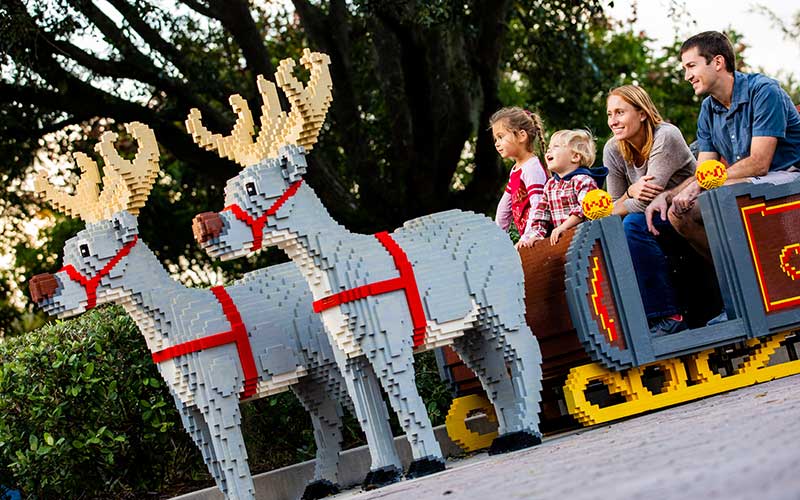 family of four seated in santas lego sleigh with reindeer at legoland florida resort
