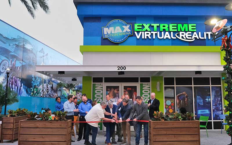 group cutting ribbon in front of new storefront building at max action arena icon park