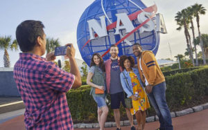 group posing with nasa globe while man takes photo at kennedy space center for real florida adventures