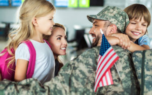 happy family and man in military uniform hugging in airport with american flag for universal military discount enjoy florida blog