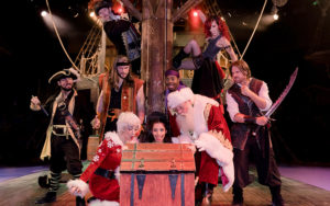 pirates and clauses stare into treasure chest on ship deck stage at pirates dinner adventure