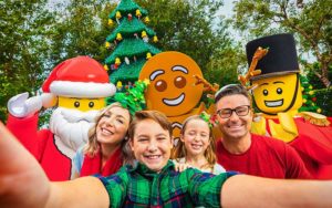 smiling family taking selfie with lego santa and christmas characters at legoland florida resort