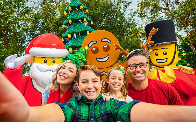 smiling family taking selfie with lego santa and christmas characters at legoland florida resort